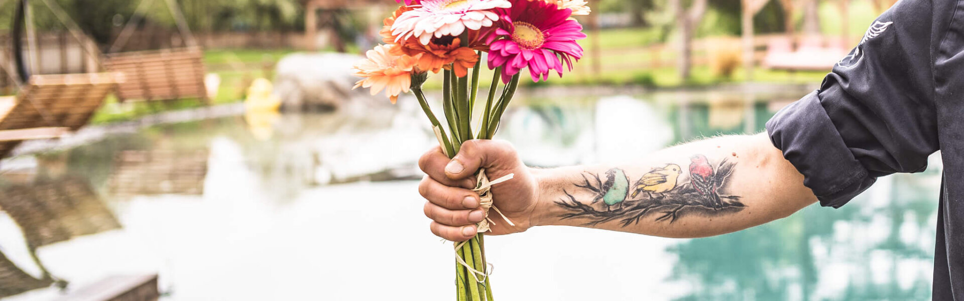 Tätovierte Hand hält einen bunten Blumenstrauß