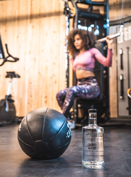 Medizinball, im Hintergrund eine Frau beim Trainieren im Gym