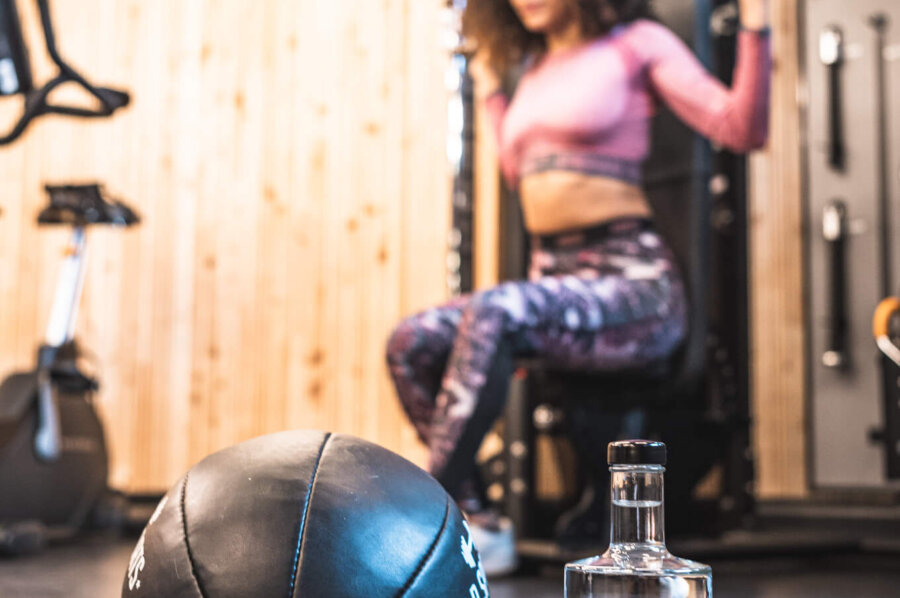 Medizinball, im Hintergrund eine Frau beim Trainieren im Gym